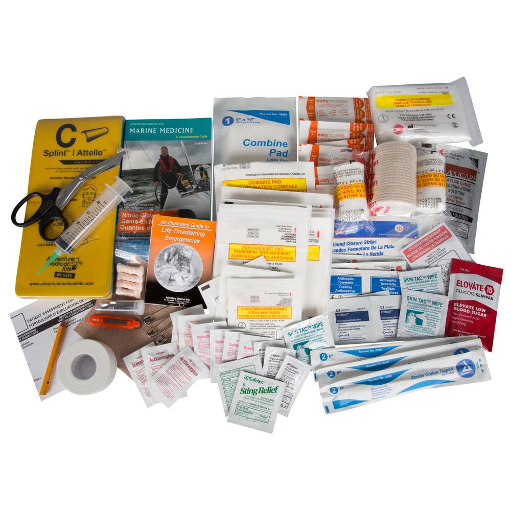 The NRS Pro Paddler Medical Kit, containing bandages, splints, scissors, gauze, medications, and instruction booklets—ideal for backcountry adventures—is neatly arranged on a white surface with other essential medical supplies and first aid items.