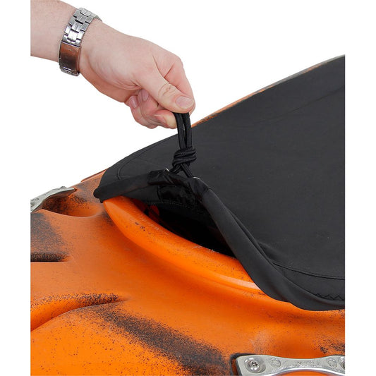 A hand lifts the edge of a black NRS Super Stretch Cockpit Cover, equipped with an adjustable shock cord, securing it to the cockpit rim of an orange kayak.