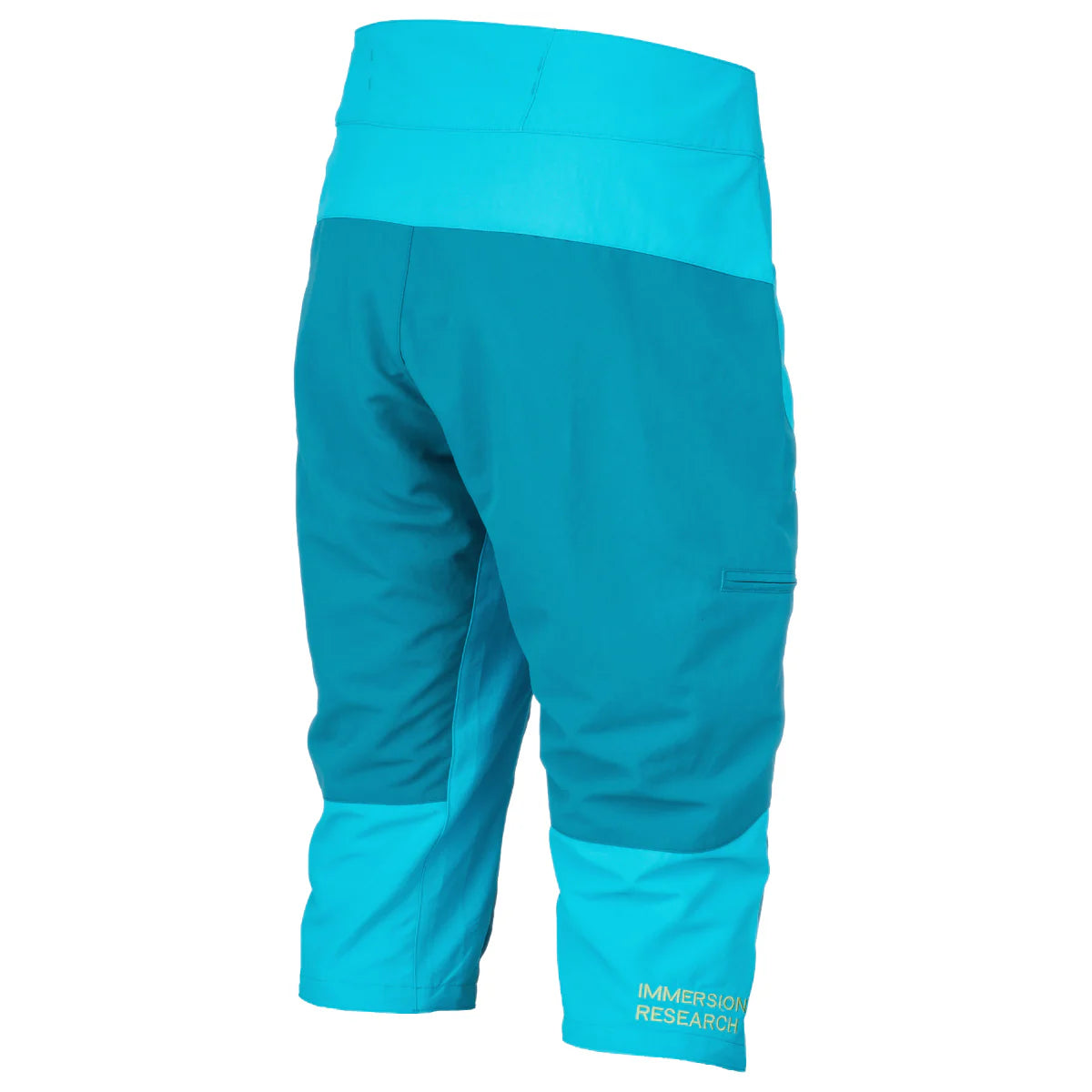 Back view of a pair of blue and turquoise knee-length waterproof Shinzer Shorts made from durable nylon taslan, with the brand "Immersion Research" printed on the lower right leg. These shorts feature an adjustable webbing belt for a secure paddling fit.