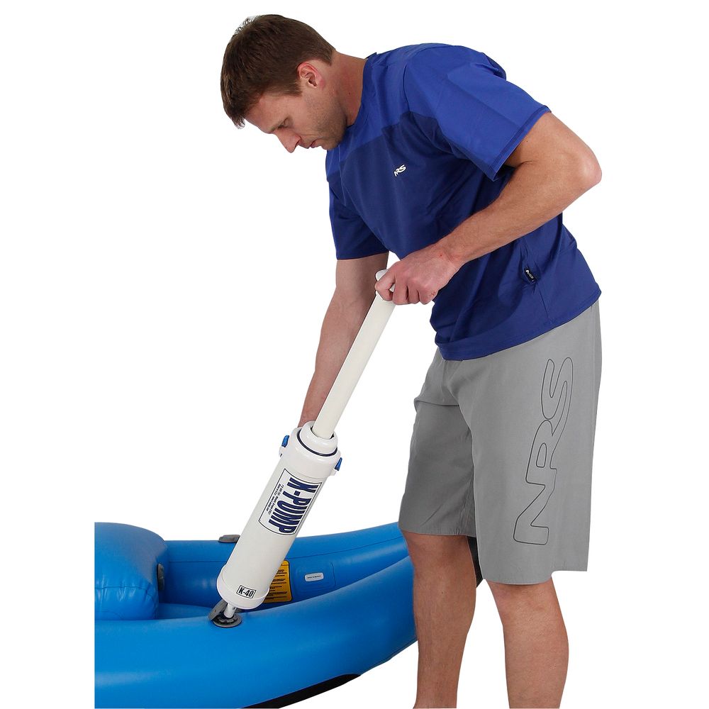 Someone in a blue shirt and gray shorts uses the NRS K-Pump K40 High Pressure, featuring a two-stage design, to inflate an inflatable raft.