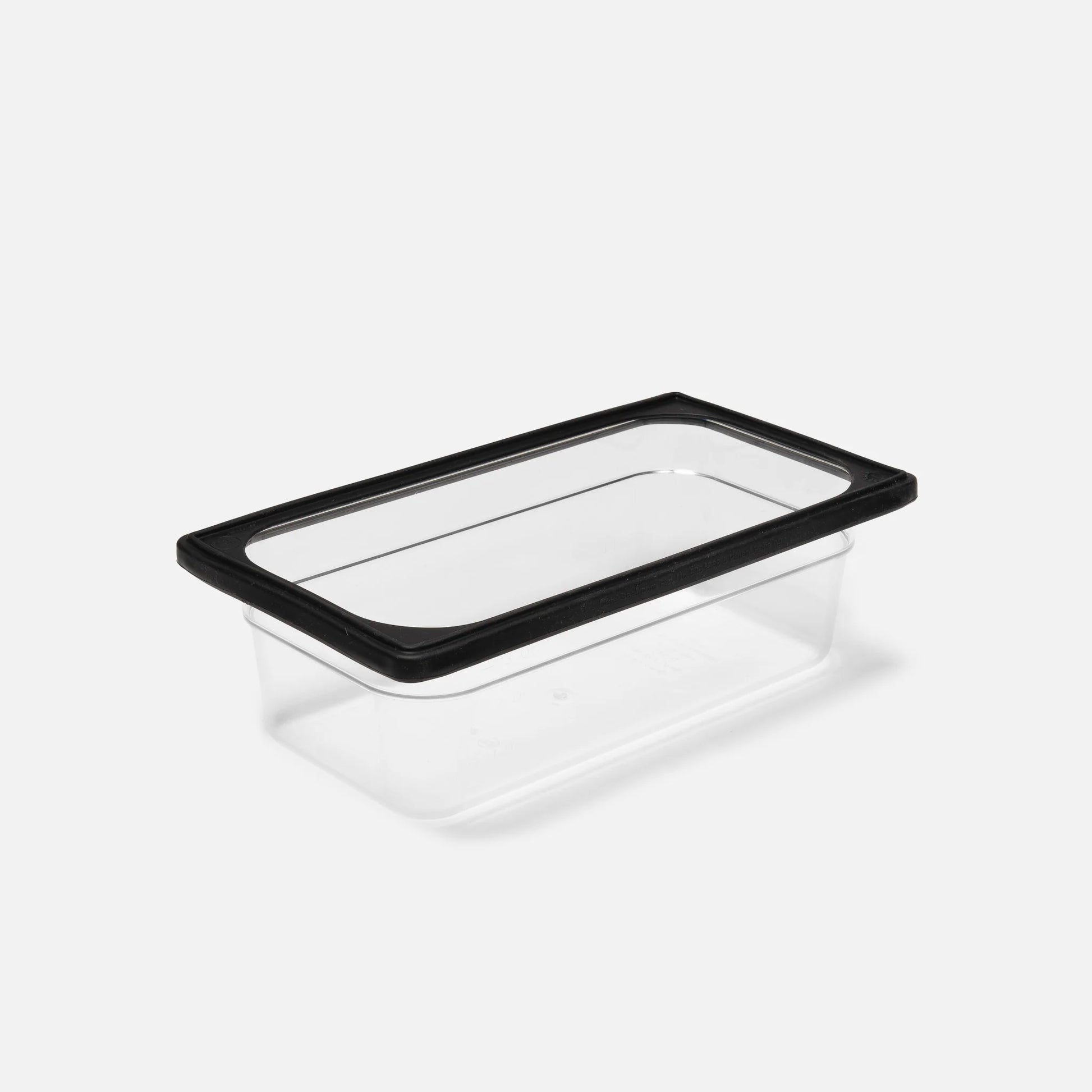 The clear rectangular Catering Pan by Canyon Coolers, made from durable polycarbonate with a black lid, stands out elegantly against the white background. Perfect for storage and serving, this versatile piece combines reliability and functionality.