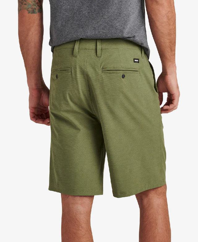 A man is wearing the Dante Short in green from REEF and a gray cotton blend shirt. He is seen from the back, hands at his sides, exuding casual comfort.