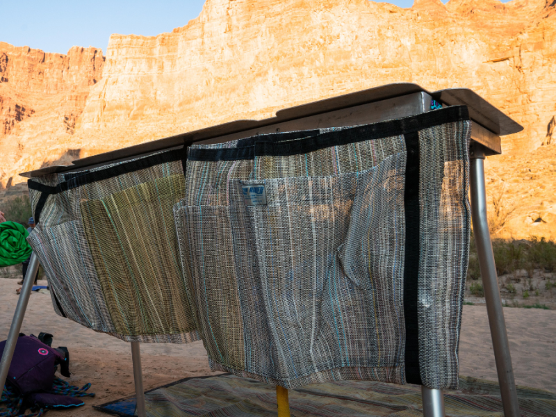 Two Dish Drying Bags from Down River Equipment, featuring woven fabric skirts and reinforced polyester webbing, are set against sunlit canyon walls.