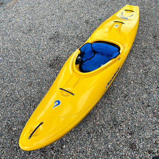 A Demo RMX 86 kayak by LiquidLogic, featuring a yellow body and a blue seat, is positioned on a gravel surface, fresh from our demo fleet.