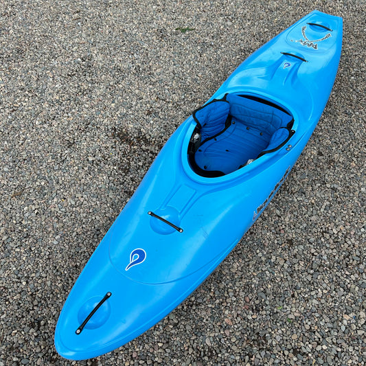 A vibrant blue Demo RMX 76 kayak by LiquidLogic, featuring a single seat and a compact storage compartment, resting on a gravel surface.