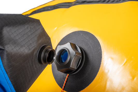 Close-up of a valve on a yellow inflatable device, with a black fitting being connected or disconnected using the Alpacka K-Pump Valve Adapter for Alpacka Rafts.