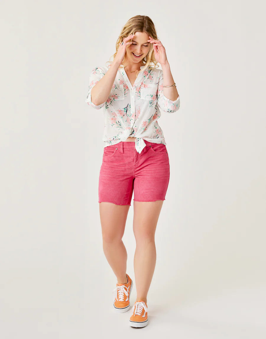 A person in a floral shirt and Carve's Oahu 4" Short smiles while standing on a light background, wearing orange sneakers.