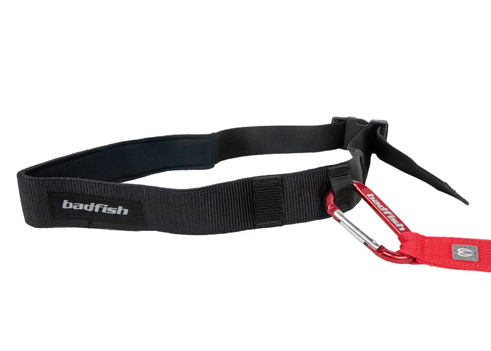 Image of a black Surf Belt with the brand name "Badfish," featuring a neoprene interior and an attached red strap secured by a red carabiner, ideal as a surf belt.