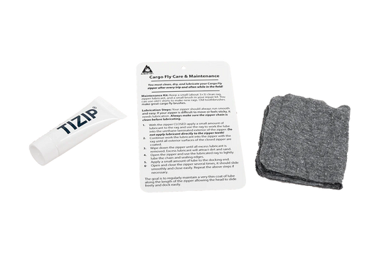 The Alpacka TiZip Maintenance Kit includes a tube marked "TIZIP," a "Cargo Fly Care & Maintenance" instruction sheet, and a folded gray cloth for optimal Cargo Fly zipper care.