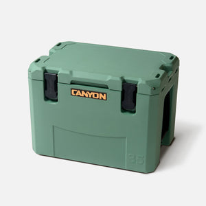 The Canyon Coolers Outfitter V2 Series has a sun-resistant green polymer build with durable black latches, an embossed "35" in the lower right corner, and a dual-action drain for easy maintenance.