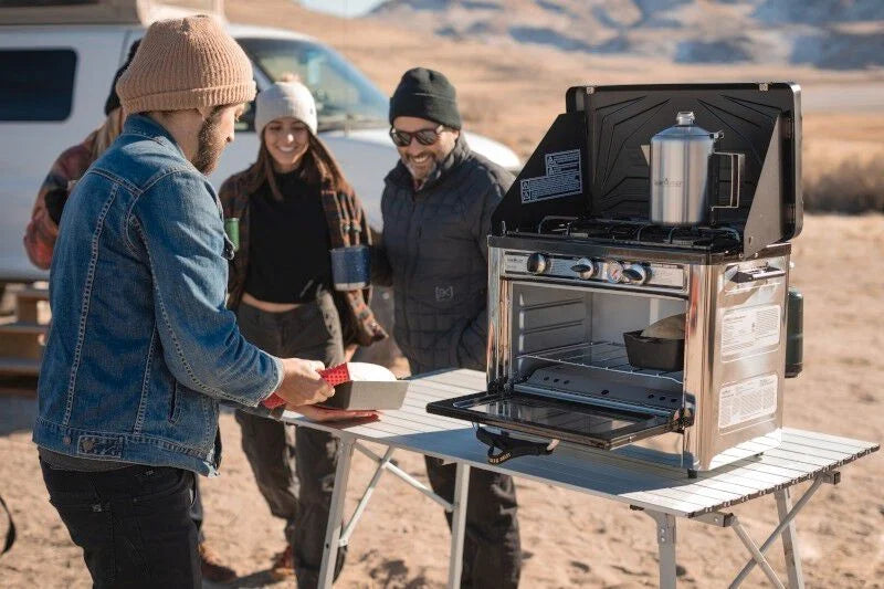 A group of people standing around a Camp Chef Mesa Adjustable Camp Table in the desert.