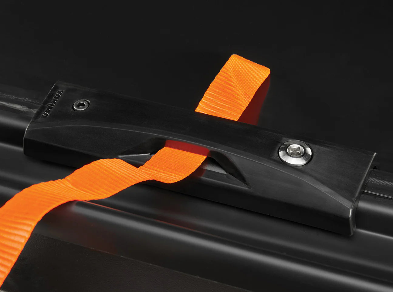 A black metal bracket secures an orange strap to keep your travel gear secure in the Yakima Skybox NX XXL cargo box, perfect for all your adventures.