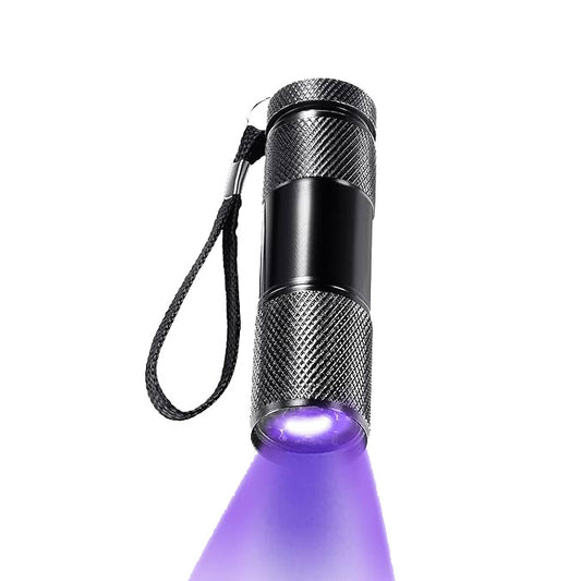 A small handheld 4CRS Blacklight Flashlight with a textured grip and wrist strap, emitting a purple beam of light, perfect for spotting spill stains or scorpion hunting.