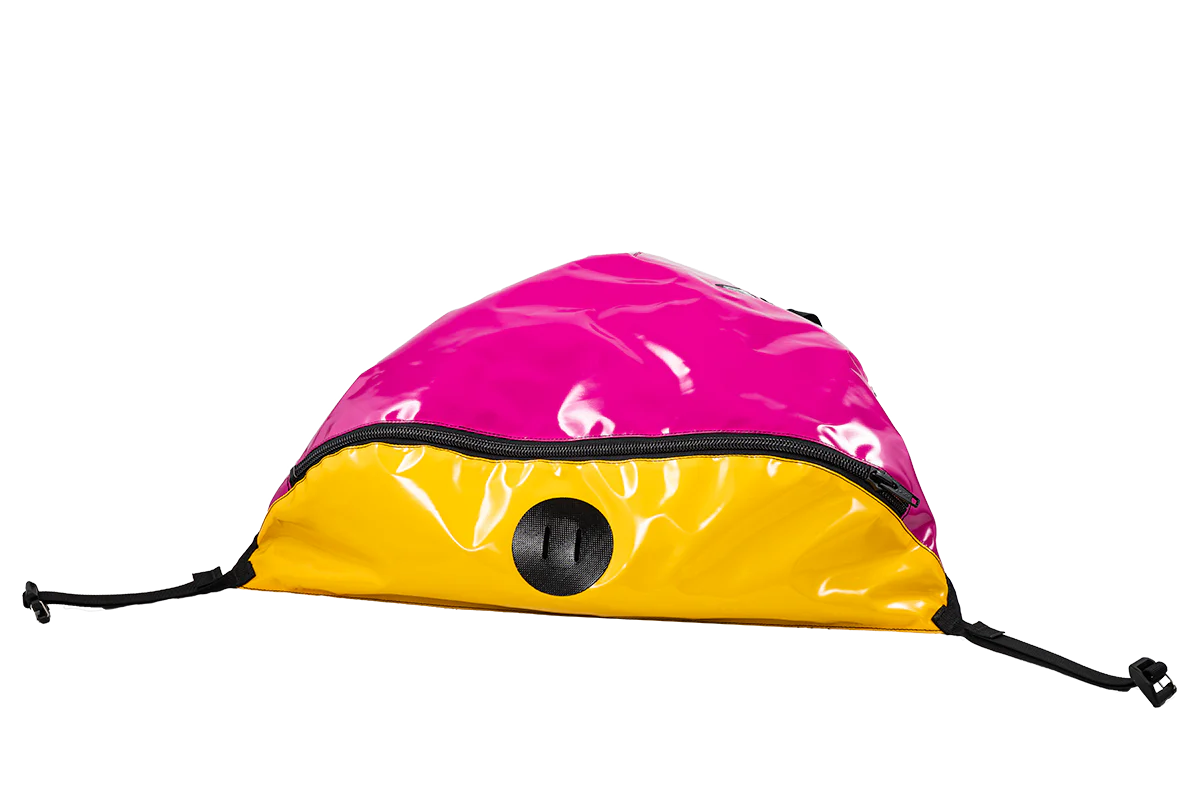 The Alpacka Hybrid Bow Bag, featuring a pink and yellow design, comes with a circular opening in the center and two black adjustable straps on both sides, making it perfect for wet storage.