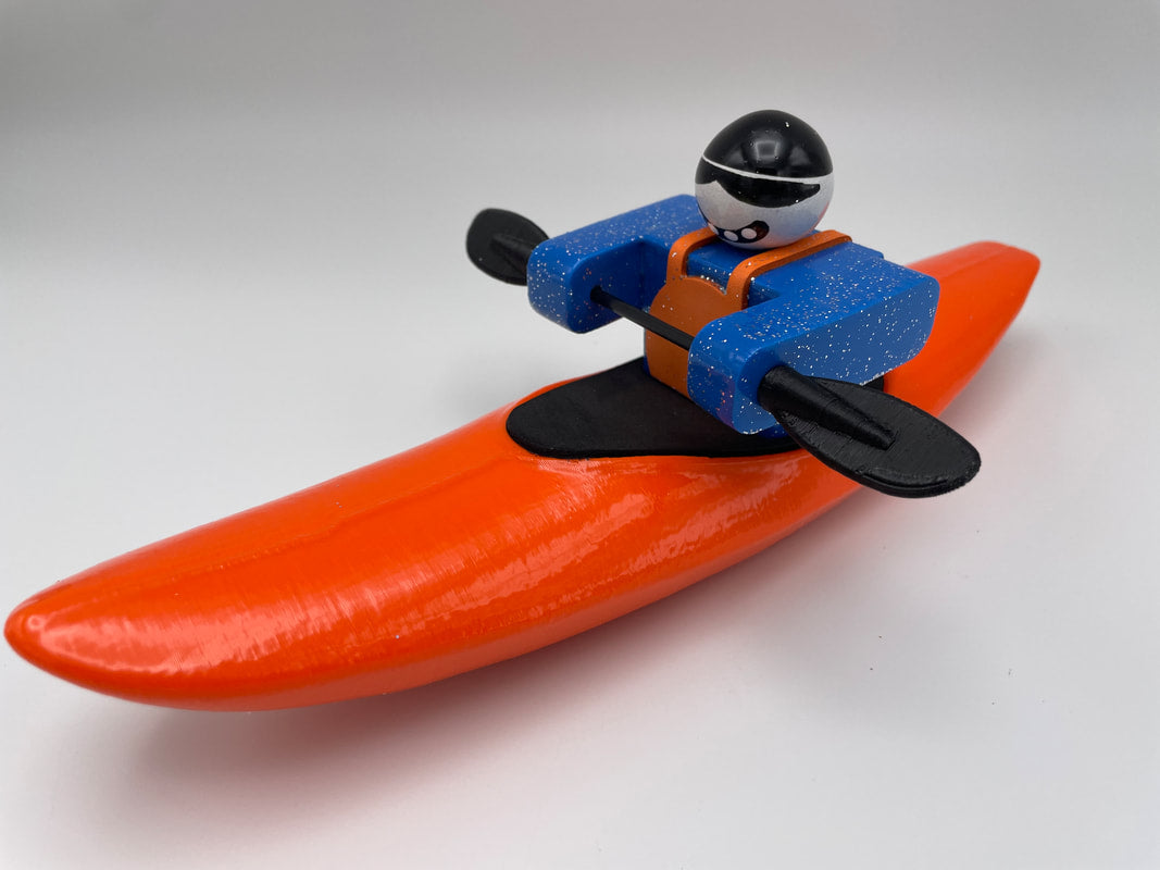 Foamie Friends' Foamie Creeker features a toy figure in a blue outfit and helmet, paddling in a vibrant orange kayak, perfect for river play against a plain background.