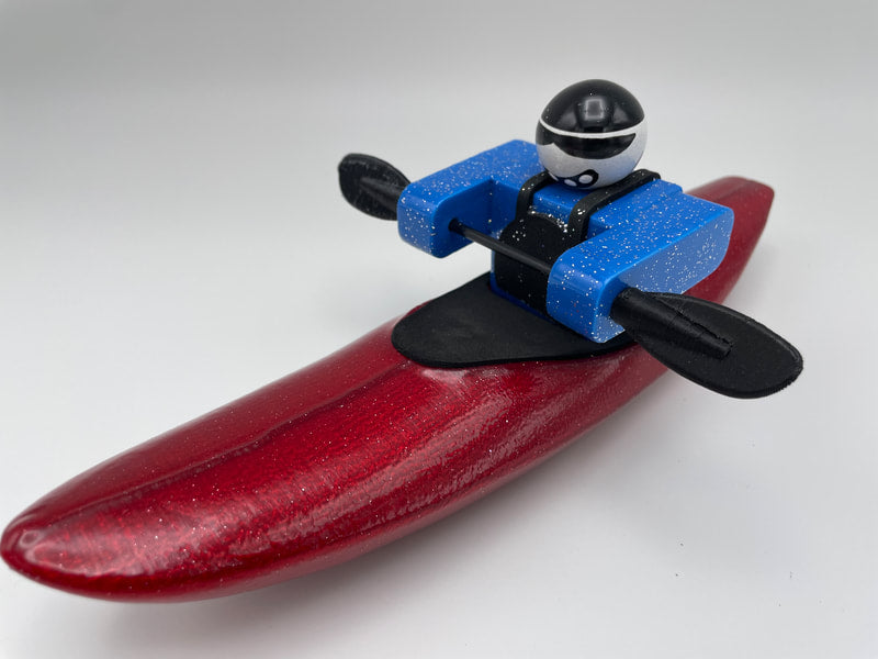 The Foamie Creeker from Foamie Friends features a toy figure in a blue suit and black helmet kayaking on a red kayak, ready for river play adventure against a plain background.