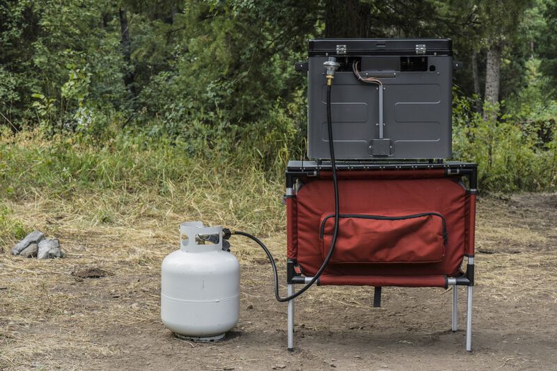 A camping chair with a Camp Chef Propane Tank Adapter Hose for a Camp Chef cooking system.