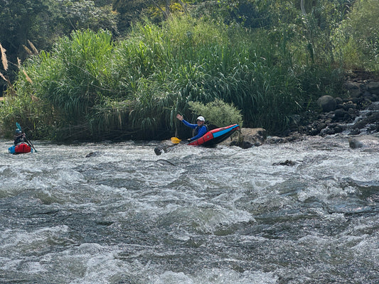 A paddlesport enthusiast expertly maneuvers an ACA Packraft Instructor Certification kayak from 4CRS Paddle School through white water rapids, with lush greenery providing a perfect backdrop for the thrilling journey.