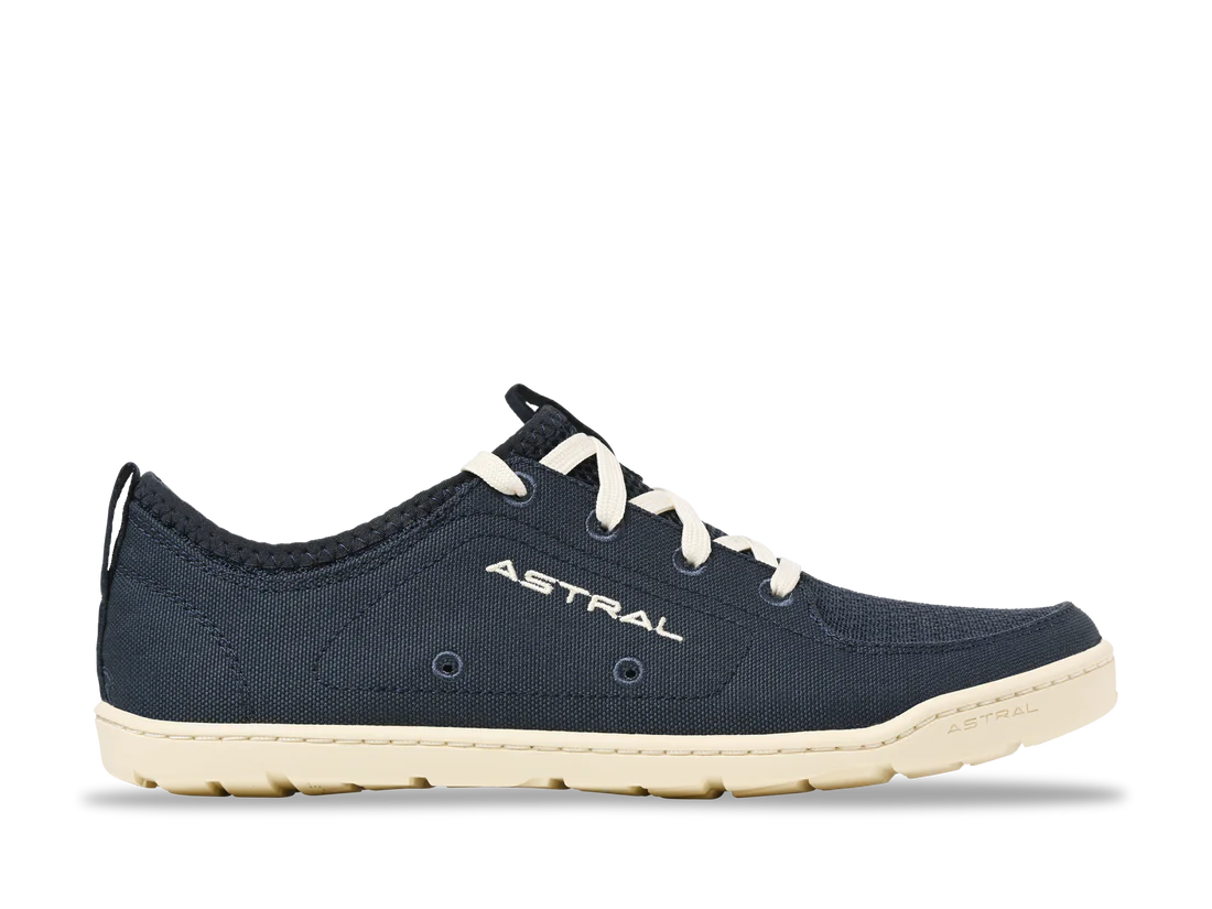 A navy blue casual sneaker with white laces and a beige sole, the "Loyak - Women's" by Astral offers a durable design. The word "Astral" is printed on the side, making it ideal for both urban strolls and kayaking adventures.