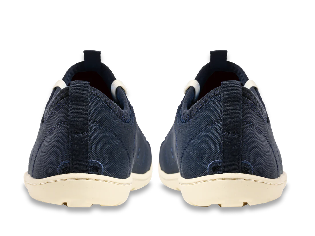 Rear view of the Astral Loyak - Women's navy blue slip-on shoes with white soles, featuring a FlexGrip outsole ideal for kayaking, against a white background.