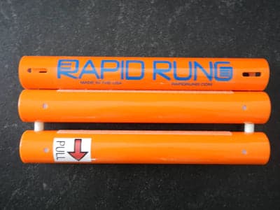 A pair of orange tubes with the word Rapid Rung Raft Ladder on them.