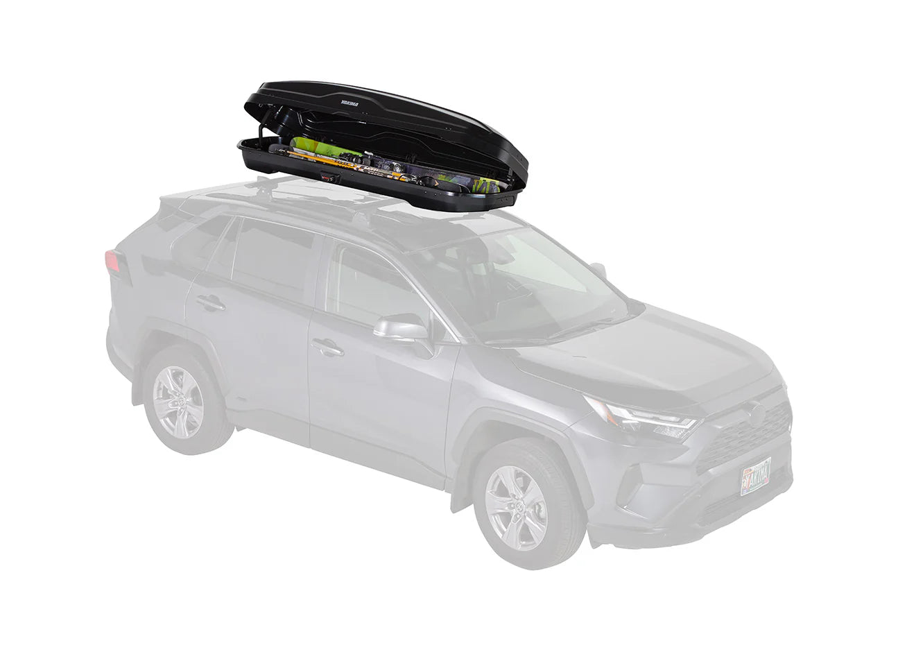 A partially transparent SUV sports a Yakima SkyBox NX Skinny on the roof, loaded with camping gear. The tool-free installation of this cargo box streamlines adventure preparation.