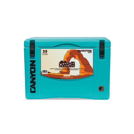 A teal-colored Canyon Outfitter Series Coolers (2023) with a capacity of 35 quarts. The cooler, which is bear proof, features a handle, latch system, and a label with brand and model information on the front. Plus, Canyon Outfitter Series Coolers (2023) come with a lifetime warranty.